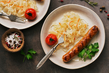 Closeup of sauerkraut with fried sausage on a dark rustic background. Overhead view, flat lay.