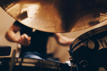 Positive handsome male with headphones playing on drums in studio