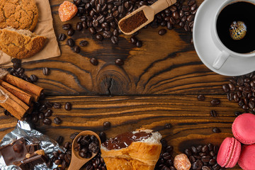 Breakfast menu food frame with a copy space. Coffee, croissants, oatmeal cookies, chocolate, cinnamons, macaroons on the wooden table