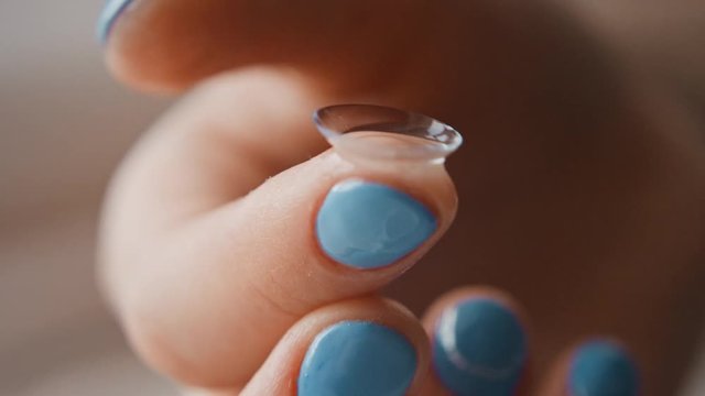 The girl takes out contact lenses from the container with the solution and touches their fingers, hands close-up. Women's fingers take lenses, crumple them and touch. Slow motion, 4K