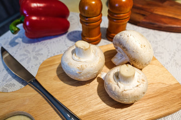 Fresh champignon mushrooms on a cutting board. Close-up. Vegetarian food.