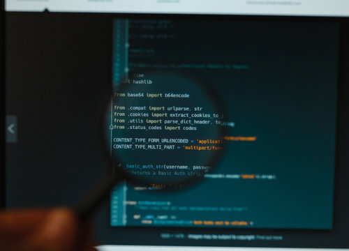 Program code illustrative concept on display screen through magnifying glass