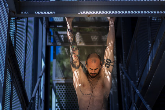 Muscular guy performing pull ups on street