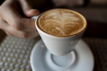 Male hand holding a white cup of coffee