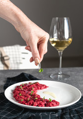 Beetroot risotto selective focus served with glass of white wine, gourmet italian food