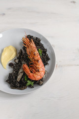Black rice with seafood, shrimps, aioli served with glass of white wine, gourmet food