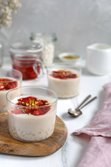 Healthy vegan dairy free dessert - tapioca pearls pudding with coconut milk and strawberry chia jam close up, served in glass jar