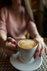 Female hand holding a white cup of coffee