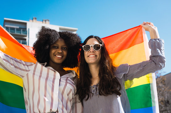 Lesbian couple celebrating with LGBT flag on gay pride day