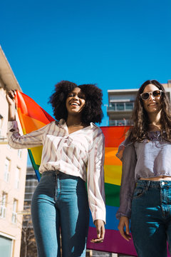 Lesbian couple celebrating with LGBT flag on gay pride day