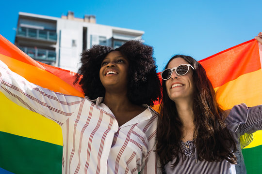 Lesbian couple celebrating with LGBT flag on gay pride day