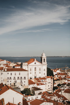 Amazing drone view of blue sky over tiled roofs of old houses and calm sea in Lisbon, Portugal