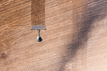 Spring agricultural work in the fields. Plowing and harrowing the soil with a tractor. The view from the top. Copy space. Concept: Timely preparation of soil for sowing is the key to a good harvest.