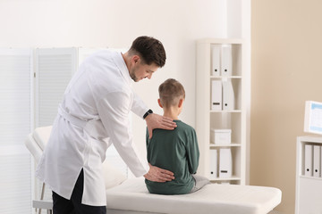 Chiropractor examining child with back pain in clinic