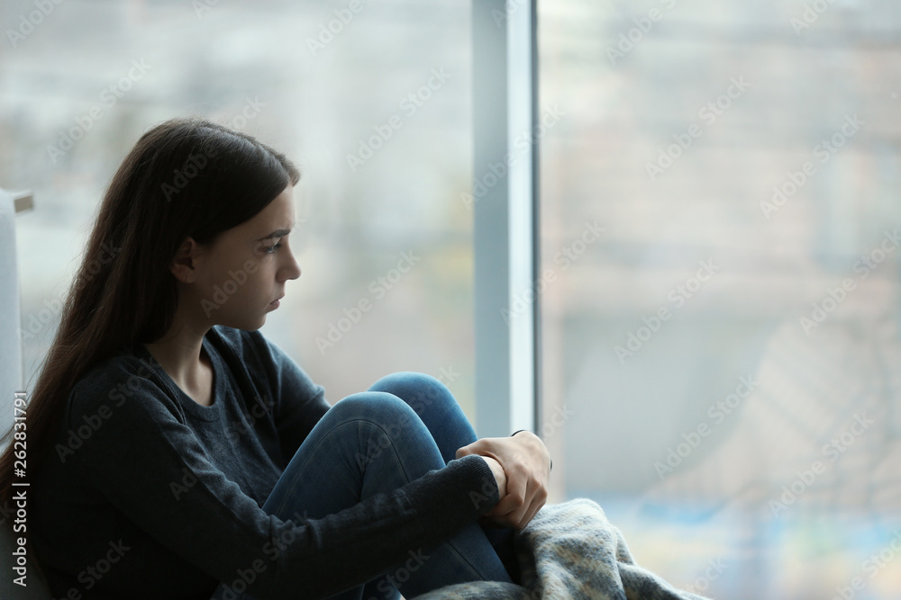 Canvas Prints upset teenage girl sitting at window indoors. space for text