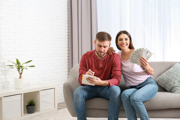 Obraz premium Beautiful young couple with money at home