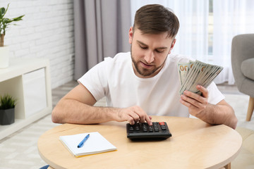Happy young man with money at home