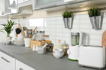 Different appliances, clean dishes and utensils on kitchen counter