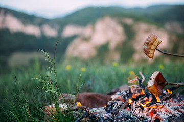 Fried bacon at campfire while camping outdoors.