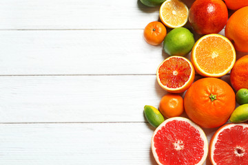 Flat lay composition with different citrus fruits and space for text on white wooden background