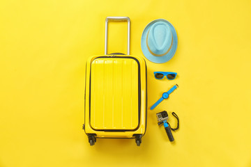 Flat lay composition with suitcase and accessories on color background