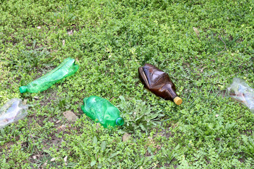Crushed plastic bottles of mineral water on the grass, the concept of environmental protection, clogging of the environment
