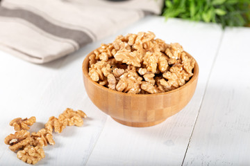 Walnut kernels in a wooden bowl on white background.