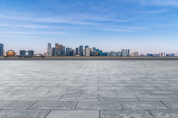 Empty square tiles and skyline of urban buildings..