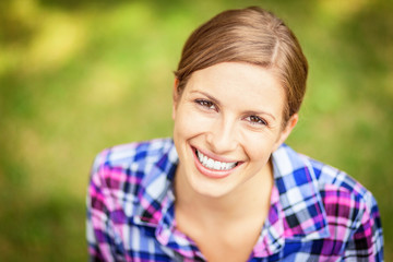 Fototapeta premium Closeup Of A woman smiling at the camera. At the park. Green background 