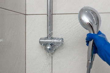 Close-up of shower mixer faucet with limescale, white chalky deposit and stains. Formed on the...