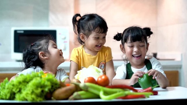 Happy children in the kitchen at home. Kid enjoy cooking the healthy food with variety of vegetable.