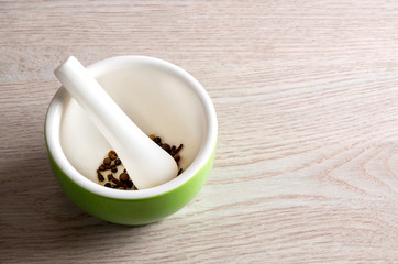 Ceramic mortar and pestle with spices on wooden table