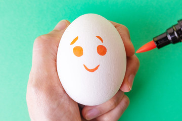 White egg with smilie painted with markers. Emotions of joy, happy. Funny Emoji on a white background. Could be used as a background. Easter. Place for text.