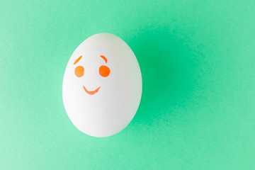 White egg with smilie painted with markers. Emotions of joy, happy. Funny Emoji on a white background. Could be used as a background. Easter. Place for text.