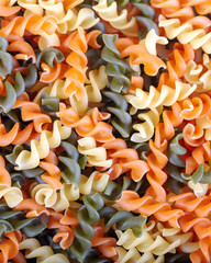 Colorful raw rutini pasta with vegetables like as background.