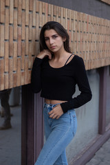 Hipster beautiful girl wearing blank t-shirt and jeans posing against rough street wall, minimalist urban clothing style, mockup for tshirt
