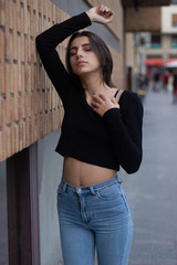 Hipster beautiful girl wearing blank t-shirt and jeans posing against rough street wall, minimalist urban clothing style, mockup for tshirt