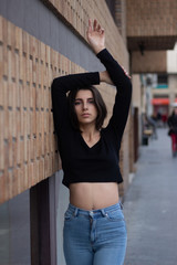 Hipster beautiful girl wearing blank t-shirt and jeans posing against rough street wall, minimalist urban clothing style, mockup for tshirt
