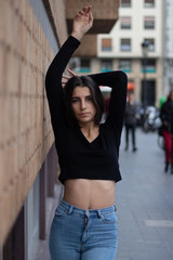 Hipster beautiful girl wearing blank t-shirt and jeans posing against rough street wall, minimalist urban clothing style, mockup for tshirt