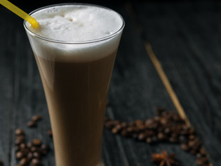 An elongated beautiful glass of latte coffee with a straw