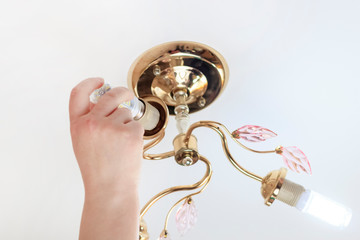 female hand inserts a light bulb into the threaded socket. she is shining. Installation of household LED lamps of corn type, in the lamp holder, there is a toning
