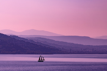 Trieste,all'alba, con le nebbie del porto vecchio e il Faro della Vittoria, e un veliero che...