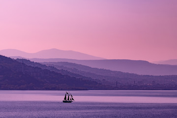 Trieste,all'alba, con le nebbie del porto vecchio e il Faro della Vittoria, e un veliero che attraversa il golfo