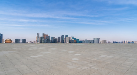 Empty square tiles and skyline of urban buildings..