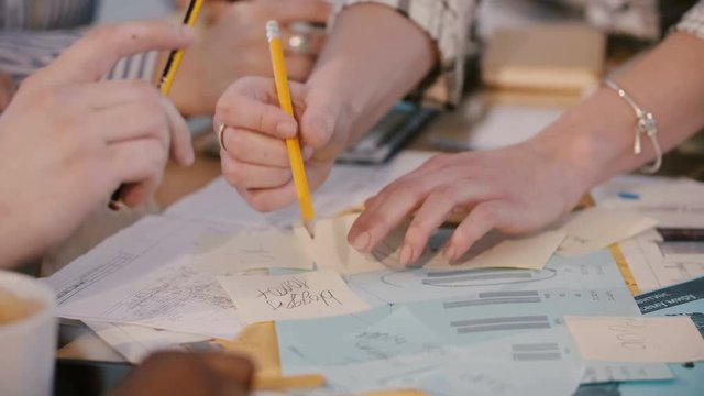 Teamwork concept, hands of business colleagues work together at corporate office meeting, write on paper notes close-up.