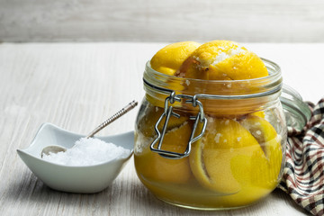 Moroccan preserved salted lemons in glass jar on white wooden table