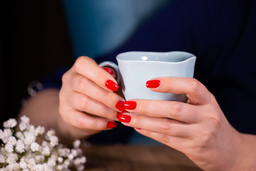 Beautiful woman hands with red manicure and cup Limited depth of field