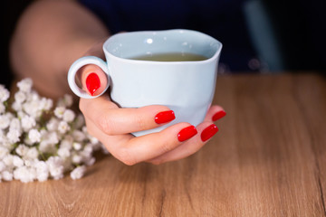 Beautiful woman hands with red manicure and cup Limited depth of field