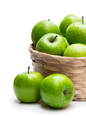 Ripe green apples in wicker basket isolated on white