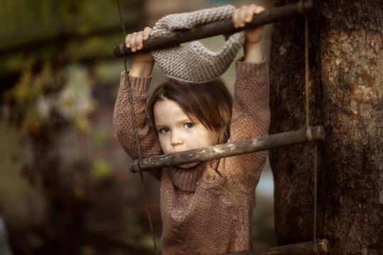 baby girl swinging on wooden rope ladder near tree